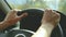 Close-up on open aperture. The girl drives a car on a country road. Women`s hands on the steering wheel