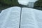 Close up of open Holy Bible in Psalm 91. Windshield with raindrops. Blurred background with expressway and cars.