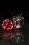 Close up of opened pomegranate next to water glass with seeds and splash