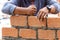 A close up of orange bricks with the hands of a mason We are building the walls of the house, designing the arrangement of bricks