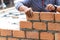 A close up of orange bricks with the hands of a mason We are building the walls of the house, designing the arrangement of bricks