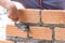 A close up of orange bricks with the hands of a mason We are building the walls of the house, designing the arrangement of bricks