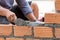 A close up of orange bricks with the hands of a mason We are building the walls of the house, designing the arrangement of bricks