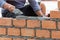 A close up of orange bricks with the hands of a mason We are building the walls of the house, designing the arrangement of bricks