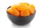 Close-up of orange colored dried apricot prunus armeniaca in a black ceramic bowl over white background