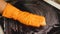 Close-up of orange glove, sponge washing the cooktop. Selective Focus. The concept of home cleaning of an electric stove