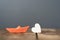 close-up of an orange miniature origami ship with a wooden heart on wooden table