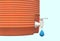 A close up of an orange plastic water cooler dispenser container dripping water droplets against a light blue backdrop