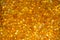 Close up of orange silica gel dessicant. Golden translucent beads with shiny light