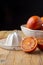 Close-up of oranges sanginas in bowl with white juicer on rustic wooden table and black background