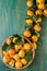 Close up of organically grown apricots. Basket full of apricots on green wooden background