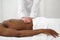 Close up of osteopath doing manipulative massage on african male abdomen on white background, copy space.