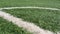 Close up of the out of bounds line on a turf football field.