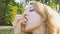 Close up outdoors portrait of young blonde woman eating french fries sitting on the bench in the park. Unhealthy eating