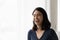 Close up overjoyed Asian woman standing near window at home