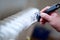 Close up of painter arm painting a heating radiator with paint roller. Professional Workman Hand holding Dirty Paintbrush.