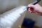 Close up of painter arm painting a heating radiator with paint roller. Professional Workman Hand holding Dirty Paintbrush.