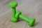 Close-up of a pair of bright green little female dumbbells on the wooden floor