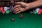 A close up of a pair of dice rolled by someone on a green felted gaming table.  Behind the throwing hand there are stacks of