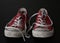 Close up of pair of sneakers - red and white vintage worn out shoes - youth hipster shoes on black background - top view