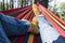 Close up of pair of trekker legs having relax outdoor leisure activity laying on a colorful hammock alone with tress forest woods
