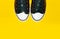 Close-up of pair vintage sneakers shoes on yellow background with copy space.