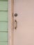 Close-up of pale pink rusty Caribbean house door, door handle, lock and light green wooden facade. Tropical Construction and