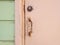 Close-up of pale pink rusty Caribbean house door, door handle, lock and light green wooden facade. Tropical Construction and