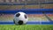 Close-up pan around a football on grass in an empty stadium