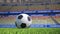 Close-up pan around a football on grass in an empty stadium