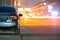 Close up of parked car on roadside at night with blurred view of traffic lights of moving vehicles on city street