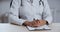 Close up part of female body of unknown woman with black skin, doctor or nurse sitting at table, wears uniform, put her