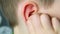 Close-up part of the head of a child, kid, scratches his ear with his hand, touches his finger inside, the concept of modern