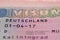 close-up part of page of document, foreign passport for travel with German visa, tourist schengen visa stamp with hologram with