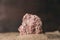 Close-up of part of pink stone sticking out of sand against dark background.