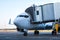 Close-up passenger jet plane parked to a boarding bridge and connected to an external power supply