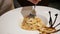 Close-up of pasta in a large plate. Woman`s hand with fork