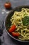Close up pasta with pesto in bowl with cherry tomatoes at black background