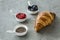 Close-up of a pastry arrangement - croissant and cups with blueberries, pomegranate and chia seeds on a gray surface