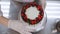 Close-up of a pastry chef decorating a cake with strawberries with mint leaves.