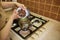 Close-up pastry chef puts organic confectionery chocolate chips into a pan for melting, standing by stove in the kitchen