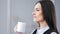 Close-up pensive elegant businesswoman enjoying drinking hot beverage from white mug