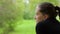 Close-up of a pensive girl with a dreamy look on the background of green trees