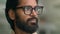 Close up pensive thoughtful calm Indian man in eyeglasses spectacles thinking dreaming looking to side. Portrait serious