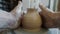 Close-up of perfect ceramic vase rotating on potter`s wheel in studio while hands shaping it