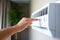 Close-up Of Person Hand Adjusting Air Conditioner On Wall, Closeup of a man hand using remote control to con, AI Generated