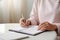 Close up of a person hands writing down notes with a pen.