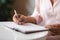 Close up of a person hands writing down notes with a pen.