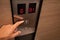 Close up of person pressing the up botton inside an elevator lift