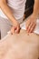 Close-up of a person receiving shiatsu treatment from a massager. Masseur presses fingers on points